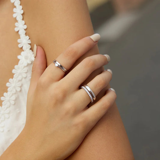 Close-up of a hand wearing two silver rings with a blurred background